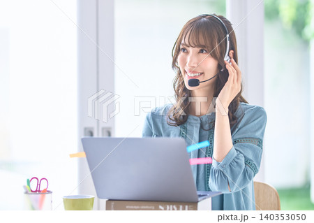 ノートパソコン越しに応対するヘッドセット姿の女性 ノートパソコン越しに応対するヘッドセット姿の女性 140353050