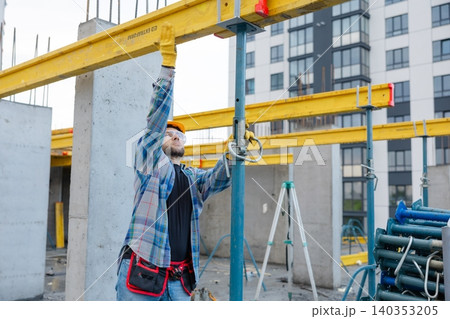 Construction worker adjusting formwork system on building site 140353205