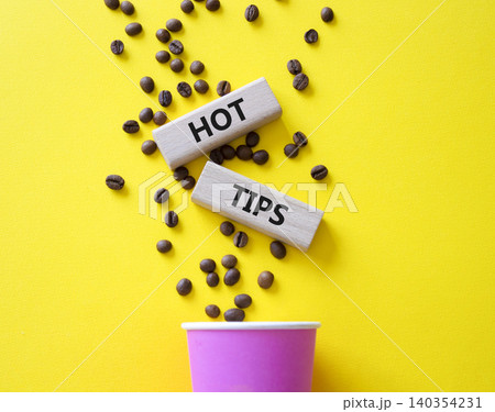 Hot Tips symbol. Concept word Hot Tips on wooden blocks. Beautiful yellow background with coffee cup. Business and Hot Tips concept. Copy space Hot Tips symbol. Concept word Hot Tips on wooden blocks. Beautiful yellow background with coffee cup. Business and Hot Tips concept. Copy space 140354231