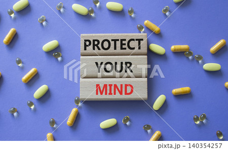 PROTECT YOUR MIND symbol. Concept words PROTECT YOUR MIND on wooden blocks. Beautiful purple background with pills. Healthcare and PROTECT YOUR MIND concept. Copy space. 140354257