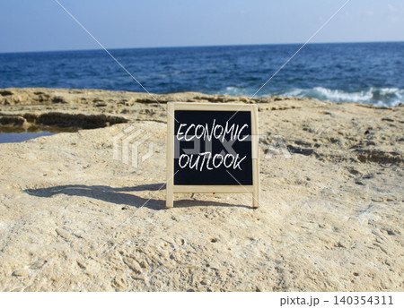 Economic Outlook symbol. White blackboard with Concept words Economic Outlook. Beautiful sea background. Business and Economic Outlook concept. Copy space. Economic Outlook symbol. White blackboard with Concept words Economic Outlook. Beautiful sea background. Business and Economic Outlook concept. Copy space. 140354311