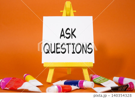 Ask Questions symbol. Wooden blocks with words Ask Questions. Beautiful orange background with paints and easel. Business and Ask Questions concept. Copy space. Ask Questions symbol. Wooden blocks with words Ask Questions. Beautiful orange background with paints and easel. Business and Ask Questions concept. Copy space. 140354328