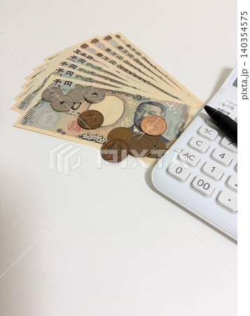 扇形に広げた新紙幣と小銭と電卓 140354575