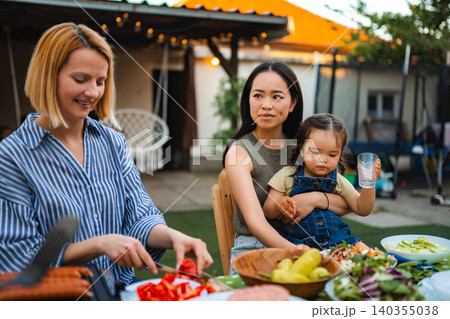 Multi ethnic family enjoying backyard barbecue picnic together 140355038
