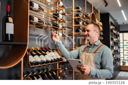 Sommelier checking wine inventory in a modern shop using a digital tablet Sommelier checking wine inventory in a modern shop using a digital tablet 140355126