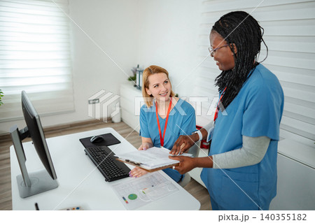 Nurses discussing patient files in hospital office Nurses discussing patient files in hospital office 140355182