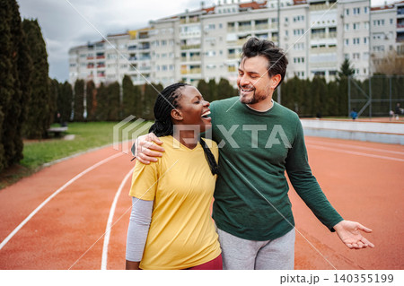 Diverse couple laughing and talking on a running track Diverse couple laughing and talking on a running track 140355199