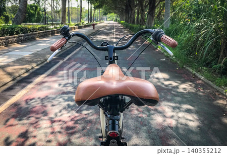 Vintage bicycle saddle and handlebars on a scenic park path Vintage bicycle saddle and handlebars on a scenic park path 140355212