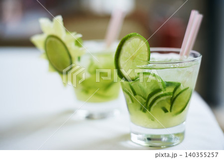 Cocktail, alcohol and glass with fruit for mojito drink on table for party, club and bar. Mockup, background and closeup of mocktail, beverage and liquid with lime, ice and liquor for celebration 140355257
