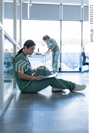 Doctor in a lab coat sitting on the floor and reading medical history of the patient Doctor in a lab coat sitting on the floor and reading medical history of the patient 140355271