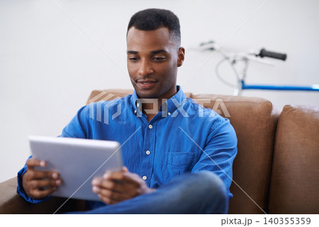Man, tablet and online for website at home, games and internet for blog or movies. Black male person, subscription and streaming entertainment on couch, video call and app for shopping on weekend 140355359