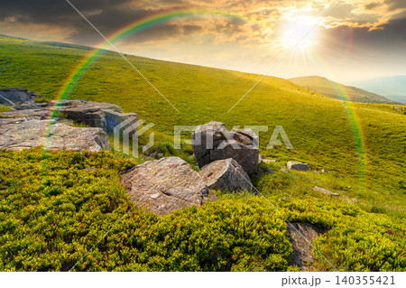 sunset over alpine meadow in summer nature. wild grass and grey rocks in carpathian landscape. mountain scenery of perechyn district, ukraine. weather with rainbow sunset over alpine meadow in summer nature. wild grass and grey rocks in carpathian landscape. mountain scenery of perechyn district, ukraine. weather with rainbow 140355421
