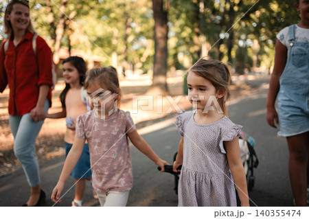 Little girls walking in the park with their teacher and classmates Little girls walking in the park with their teacher and classmates 140355474