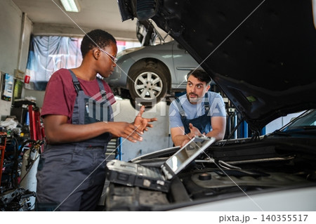 Mechanics discussing about car malfunction using diagnostic software in auto repair shop Mechanics discussing about car malfunction using diagnostic software in auto repair shop 140355517