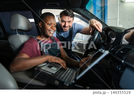 Mechanics using diagnostic software on laptop in car at repair shop Mechanics using diagnostic software on laptop in car at repair shop 140355529