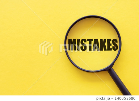 The word mistakes is written on a magnifying glass on a yellow background. The word mistakes is written on a magnifying glass on a yellow background. 140355680