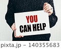 Girl holding a card with text you can help 140355683