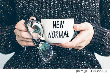 The new normal after COVID-19. Coronavirus pandemic concept. Cap with text girl holds in ypur hahds The new normal after COVID-19. Coronavirus pandemic concept. Cap with text girl holds in ypur hahds 140355684
