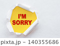 Top view of white torn paper and the text I'M SORRY on a yellow background. 140355686