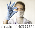 Doctor holding a pill, looking at it and giving it as a treatment to the patient 140355824