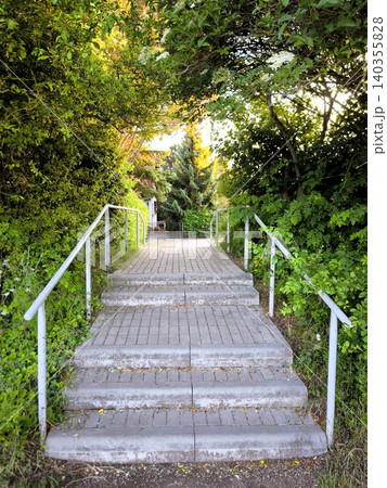 Stone staircase steps with a railing in a green park. Stone staircase steps with a railing in a green park. 140355828