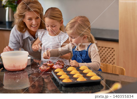 Granny, children and smile for teaching, baking and bonding together in retirement at home. Happy, senior citizen and girl with cupcake, laugh and icing for creative, family and fun in kitchen 140355834