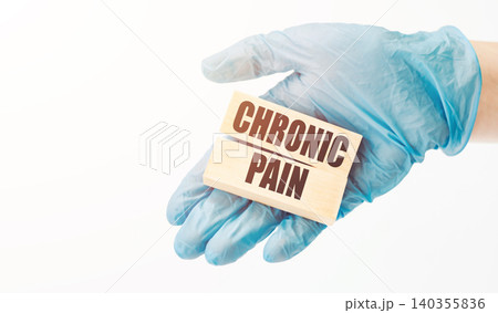 The doctor's hand in a blue glove shows wooden cubes with the text "Chronic pain". Medical concept. The doctor's hand in a blue glove shows wooden cubes with the text "Chronic pain". Medical concept. 140355836