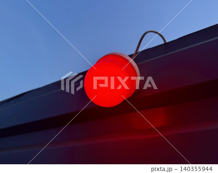 Close-up red warning light glowing on construction fence at night, blurred industrial background with bokeh, work zone safety concept 140355944