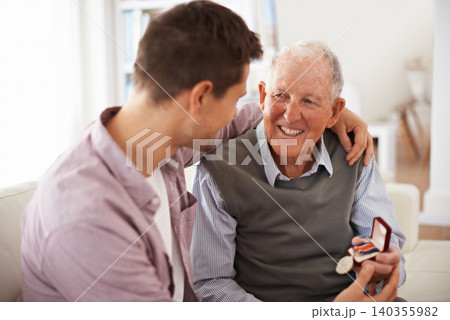 Father, adult son and medal for present support and congratulations with celebration and bonding at home. Men in living room, family time with reward or award as gift for happiness and gratitude 140355982