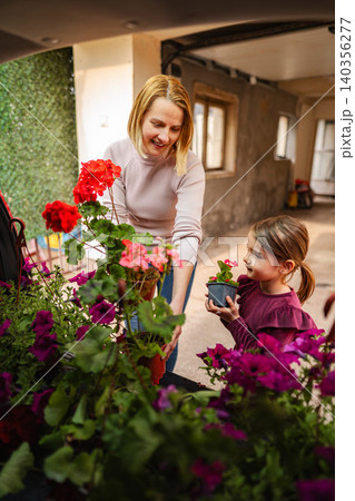 Mother and daughter bonding while planting flowers outdoors 140356277