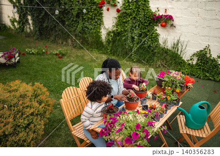 Family enjoying gardening together planting flowers in backyard Family enjoying gardening together planting flowers in backyard 140356283