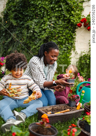 Happy family gardening together in backyard planting flowers 140356286