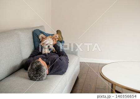 A man and his dog are laying on a couch A man and his dog are laying on a couch 140356654