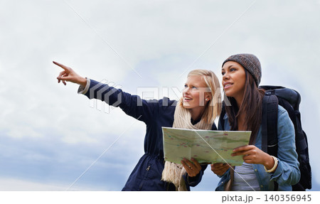 Woman, friends and pointing with map for direction or location on hiking adventure together in nature. Young female person, hiker or team with travel guide for destination, route or outdoor path 140356945