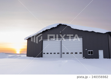 Warehouse in snow, industrial building in sunset light in winter. Warehouse in snow, industrial building in sunset light in winter. 140356982