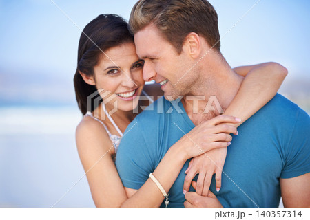 Portrait, couple and smile for hug, seaside and fun date on sunny afternoon in New Zealand. Embrace, man and woman in love for sweet relationship, romance and bonding together on weekend getaway 140357314