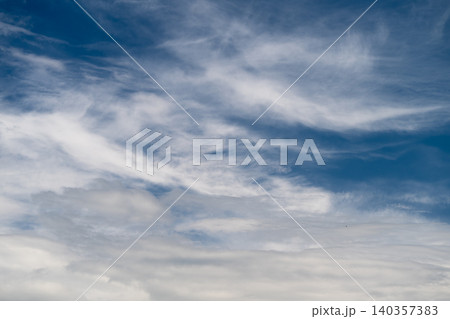 Calm atmosphere with cloud layers. Gentle clouds stretch across tranquil sky. Peaceful sky presents calm and expansive scene filled with gentle clouds and subtle colors 140357383