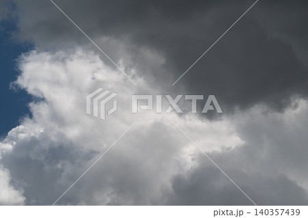 Storm clouds forming. Gray skies with impending rain. Dark storm clouds congregate over vibrant blue sky. Heavy gray thunderhead looms with layered tops and brooding edges 140357439