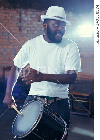 Smiling, black man and playing drum or music for event, concert with percussion and entertainment. Festival, performance and beats on rhythm for band of a creative on stage with white shirt and hat Smiling, black man and playing drum or music for event, concert with percussion and entertainment. Festival, performance and beats on rhythm for band of a creative on stage with white shirt and hat 140358574