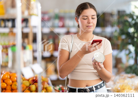 Young woman scanning qr code of canned food Young woman scanning qr code of canned food 140362111