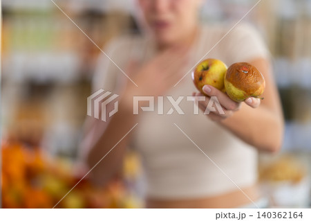 Woman holds rotten apples in grocery store Woman holds rotten apples in grocery store 140362164