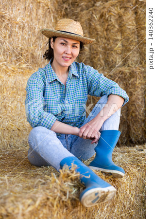 Asian woman farmer resting on hayloft Asian woman farmer resting on hayloft 140362240