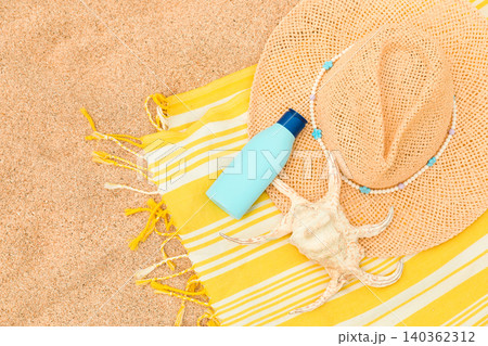 Sunhat, sunscreen, and shell placed on beach towel Sunhat, sunscreen, and shell placed on beach towel 140362312