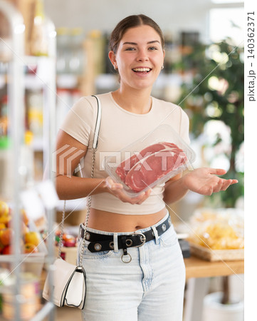 Young woman choose raw beef meat for roasting in store Young woman choose raw beef meat for roasting in store 140362371