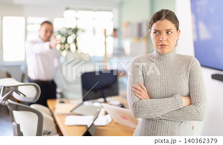 Young businessman of a large company, scolds his employee girl sitting at workdesk in office Young businessman of a large company, scolds his employee girl sitting at workdesk in office 140362379