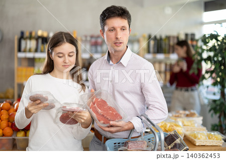 Man and his teenage daughter choosing hamburger or beef entrecote in grocery 140362453