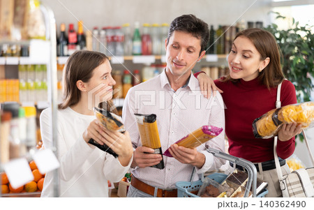 man and woman with girl choosing pasta in grocery man and woman with girl choosing pasta in grocery 140362490