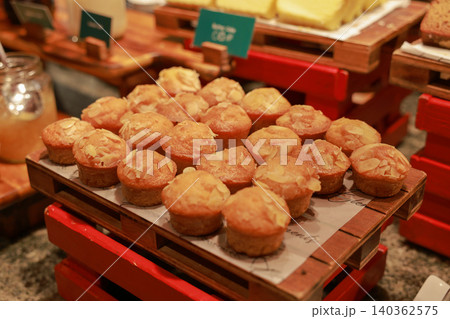 Freshly baked mini almond muffins topped with sliced nuts served on a wooden tray at a hotel breakfast buffet. Delicious sweet dessert pastry for morning brunch catering and bakery display. 140362575