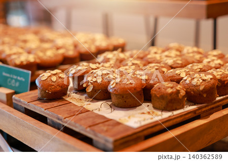 Freshly baked healthy mini banana oat muffins topped with rolled oats on a wooden tray at a luxury hotel breakfast buffet. Delicious sweet bakery dessert pastry for morning brunch food catering. Freshly baked healthy mini banana oat muffins topped with rolled oats on a wooden tray at a luxury hotel breakfast buffet. Delicious sweet bakery dessert pastry for morning brunch food catering. 140362589
