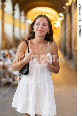 In evening, young smiling girl walks along city street Placa Real 140362602
